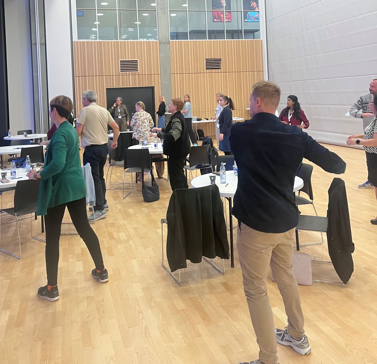 Workshopdeltagere står op og bevæger sig sammen mellem bordene